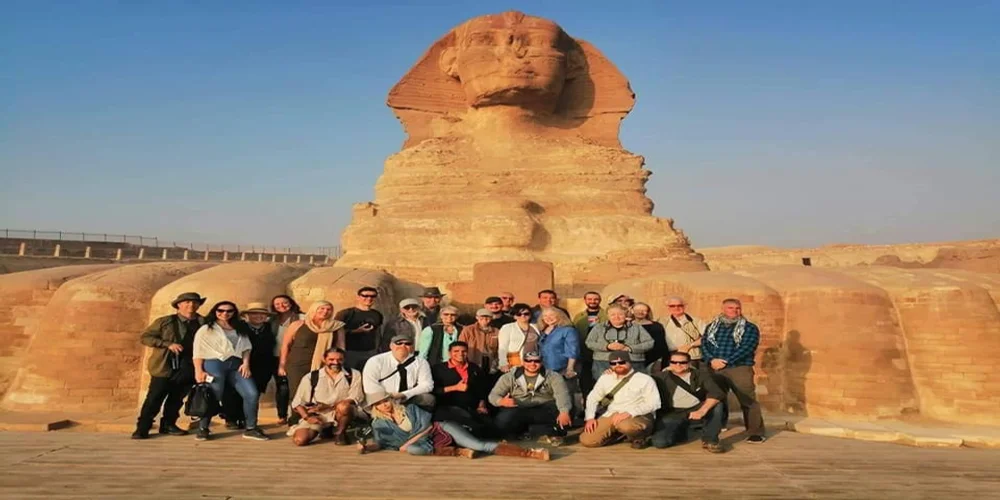 A large group of travelers posing in front of the Great Sphinx of Giza during their premium Egypt Luxury Holidays experience.